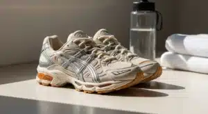 Asics Gel 1130 sneakers beiges posées sur surface en bois avec éclairage naturel et accessoires sport